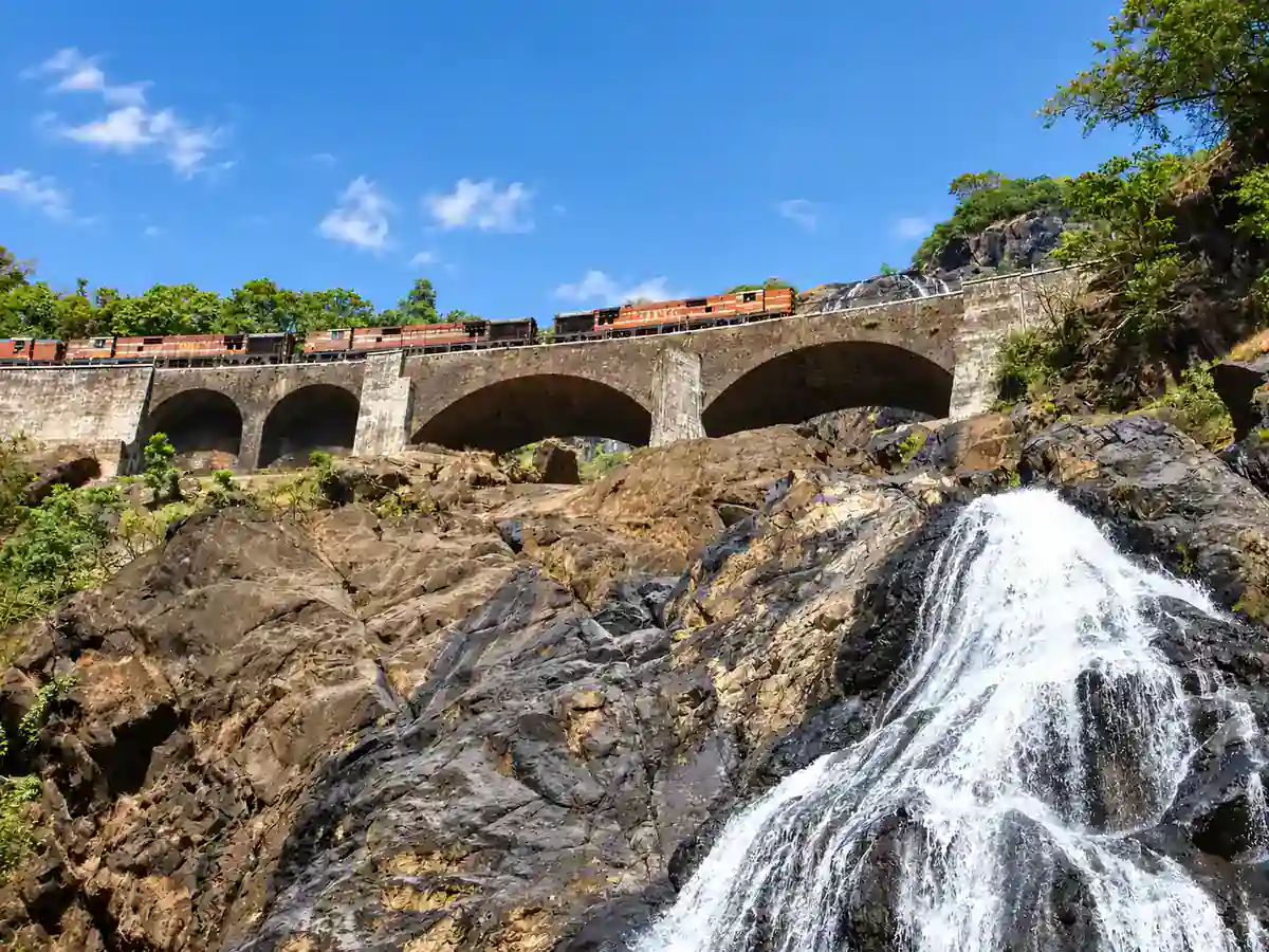 Dudhsagar Falls cascading down dark rock below a stone railway bridge in the Western Ghats of Goa